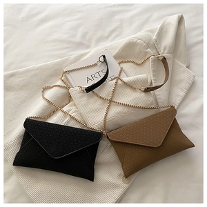 Detail of woven texture envelope bags in black and brown with gold chain straps