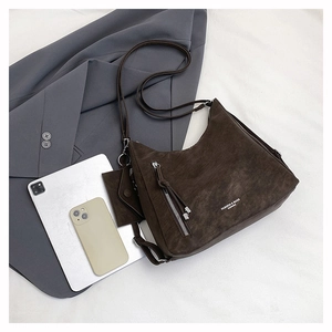 Detail of dark brown large capacity shoulder bag with tassel zipper and tablet for scale