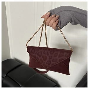 Détail du sac enveloppe bordeaux avec gaufrage léopard et bandoulière dorée
