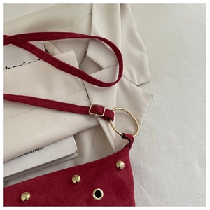 Détail du sac à bandoulière en daim rouge avec clous dorés et boucle à anneau rond