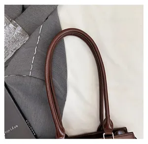 Detailansicht der dunkelbraunen Handtasche mit runden Griffen und silbernen Metallringen