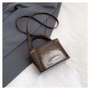 Detail of the brown glossy patent leather box bag with handle and metal zipper