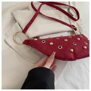 Détail du sac demi-lune bordeaux en daim avec rivets dorés et anneaux métalliques