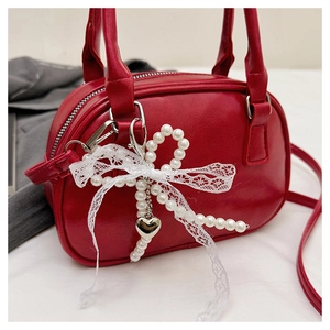 Détail du petit sac rouge avec breloque nœud en dentelle perlée et cœur doré