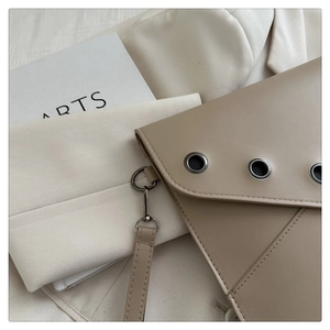 Detail of beige faux leather shoulder bag with metal eyelets and premium stitching