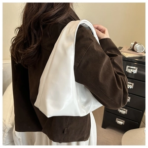 Side view of white patent leather hobo shoulder bag worn by model in retro style