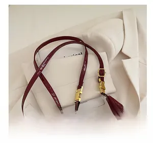 Close-up of glossy wine red patent leather shoulder bag with gold metal buckle detail