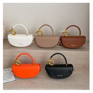Detailed view of semi-circular leather handbags with unique gold twisted metal handles