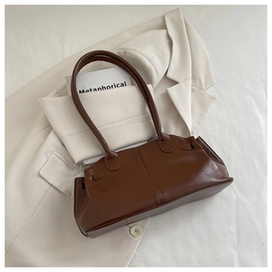 Detailed view of brown leather baguette bag with dual shoulder straps on a blazer