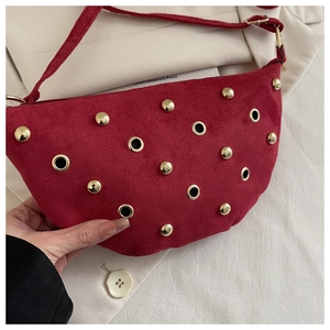 Détail du sac croissant rouge avec des rivets dorés et des œillets métalliques