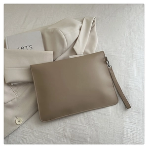 Detail of khaki rivet retro handbag with smooth PU leather texture and detachable wrist strap