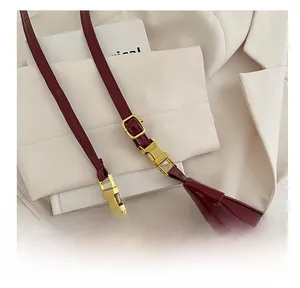 Detail of burgundy glossy patent leather shoulder strap with gold metal buckle hardware