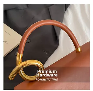 Detail of premium gold-toned twisted ring hardware on a textured brown leather handbag