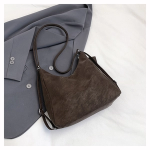 Detail of adjustable silver buckle and soft brown suede texture on a versatile tote bag