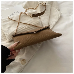Detail of brown envelope bag with wheat-grain embossing and elegant gold chain strap