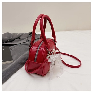 Détail du mini sac en similicuir rouge avec nœud en dentelle blanche et breloque perle
