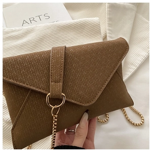 Close-up of brown envelope crossbody bag with herringbone texture and gold chain strap