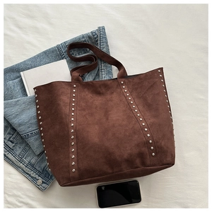 Macro detail of brown suede tote bag featuring silver studs and premium texture