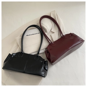 Detail of elegant black and burgundy pleated bag with glossy leather texture and long straps