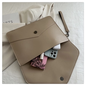 Flat lay of khaki rivet envelope clutch showing spacious interior and wristlet strap