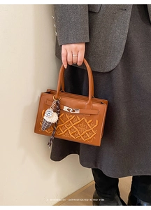 Detail view of brown woven handbag with silver clasp and ice cream plush charm