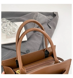 Detailed top view of brown faux leather handbag showing dual handles and zipper closure