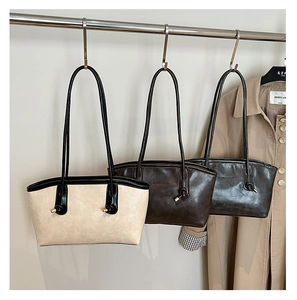 Close-up of three faux leather tote bags in cream, brown, and black with knot detail