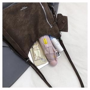 Detail view of large dark brown suede tote bag showing spacious interior and accessories