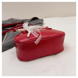 Vue détaillée du sac en cuir rouge avec nœud en dentelle et chaîne de perles élégante
