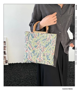 Detail of vintage floral canvas tote bag featuring natural bamboo handles and retro print
