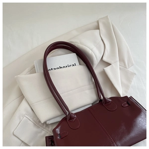 Detail of dark red pleated shoulder bag with long handles and fine stitching textures