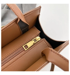 Detail view of smooth brown faux leather texture and gold metal zipper closure