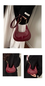 Detailed view of burgundy patent leather crescent bag with adjustable strap and gold hardware
