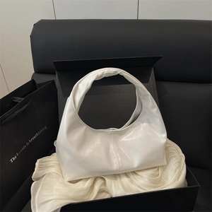 Minimalist white glossy crescent handbag displayed in a black gift box with silk fabric