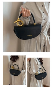 Detail of black saddle bag featuring gold metal knot accents and fashion brand lettering