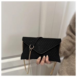 Detail of black woven envelope bag featuring elegant gold chain strap and metal buckle