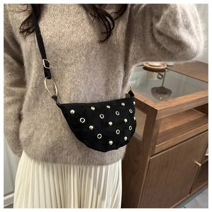 Détail du sac demi-lune noir en daim avec rivets dorés et décorations d'oeillets
