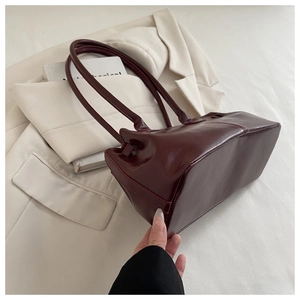Detail of burgundy glossy leather handbag showing reinforced stitching and base craftsmanship