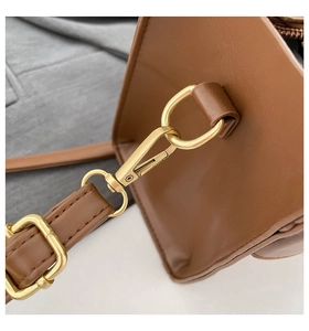 Close-up of light gold metal hooks and stitching details on a dark brown leather bag