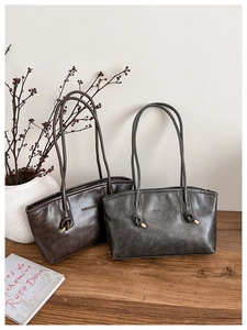Detail of minimalist leather shoulder bags in brown and grey colors on a wooden table