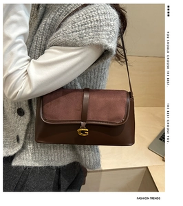 Close-up of retro dark brown leather underarm bag with gold metal buckle detail