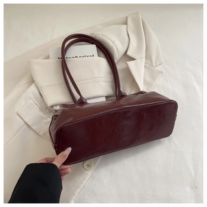 Detailed top view of wine red faux leather tote bag with slender straps on beige fabric