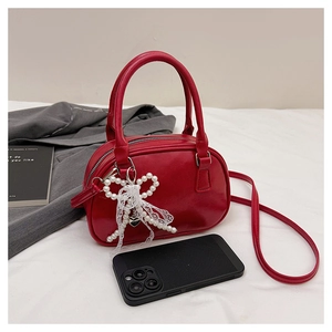 Détail du sac Boston rouge avec pendentif nœud en perles et bordure en dentelle avec téléphone