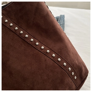 Detail of dark brown suede tote bag featuring metallic rivet studs and premium stitching