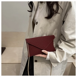 Close-up of a burgundy envelope bag with V-shaped quilting and a gold chain strap
