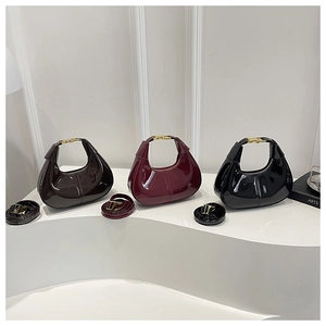 Close-up of patent leather crescent bags in brown, burgundy, and black with gold clasps