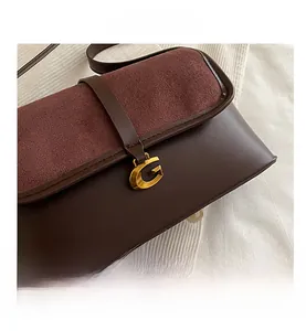 Detailed close-up of dark brown leather handbag with vintage golden G-shaped buckle hardware