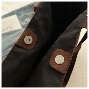 Close-up of double magnetic snap closure and suede texture on brown tote bag