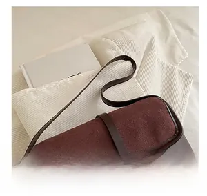 Detail of vintage dark brown patchwork shoulder bag with gold metal buckle on soft fabric