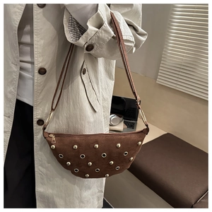 Vue détaillée d'un sac demi-lune en daim marron avec rivets dorés et œillets métalliques